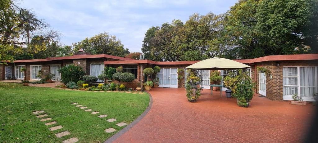 a brick house with an umbrella in a yard at Bloemhoek Guest House in Centurion