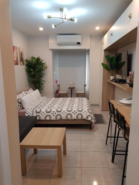 a bedroom with a bed and a table and a kitchen at Apartment 2 Quezon City Condo Pool View in Manila