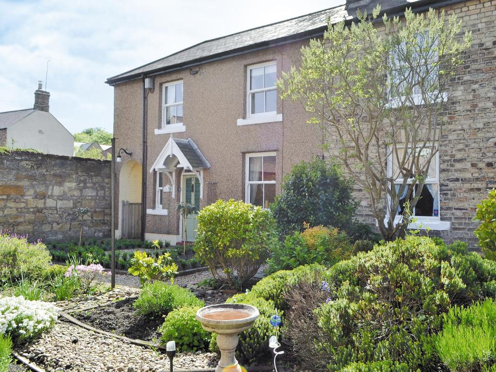 a garden in front of a brick house at Cosy Cottage in Warkworth