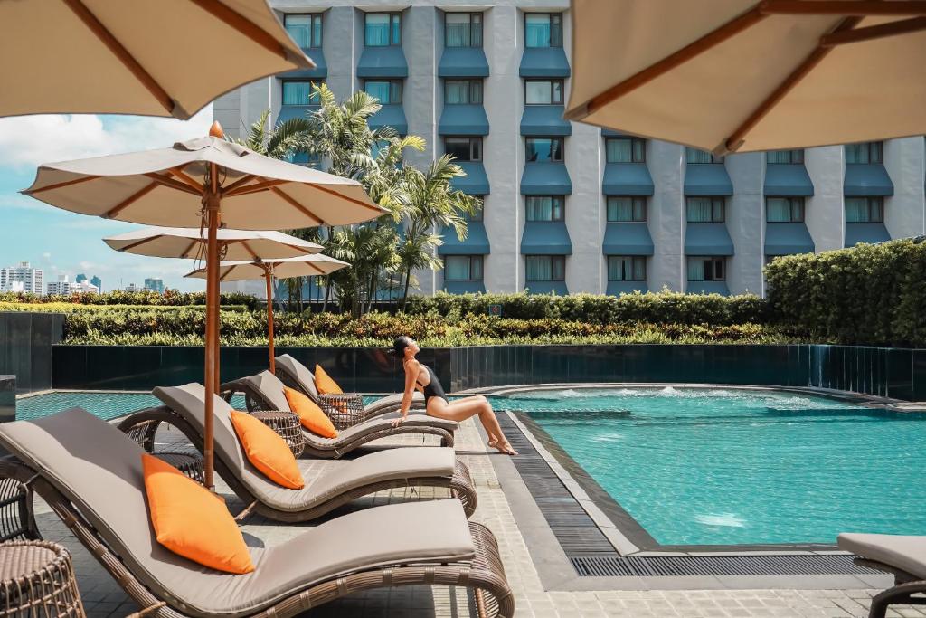 a woman sits on the lounge chairs by the pool at a hotel at Hotel JAL City Bangkok in Bangkok
