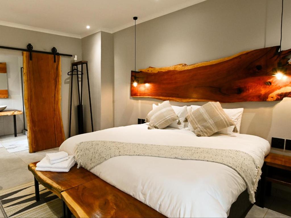 a bedroom with a large bed with a wooden headboard at The Roaming Goat Guesthouse in Toekoms