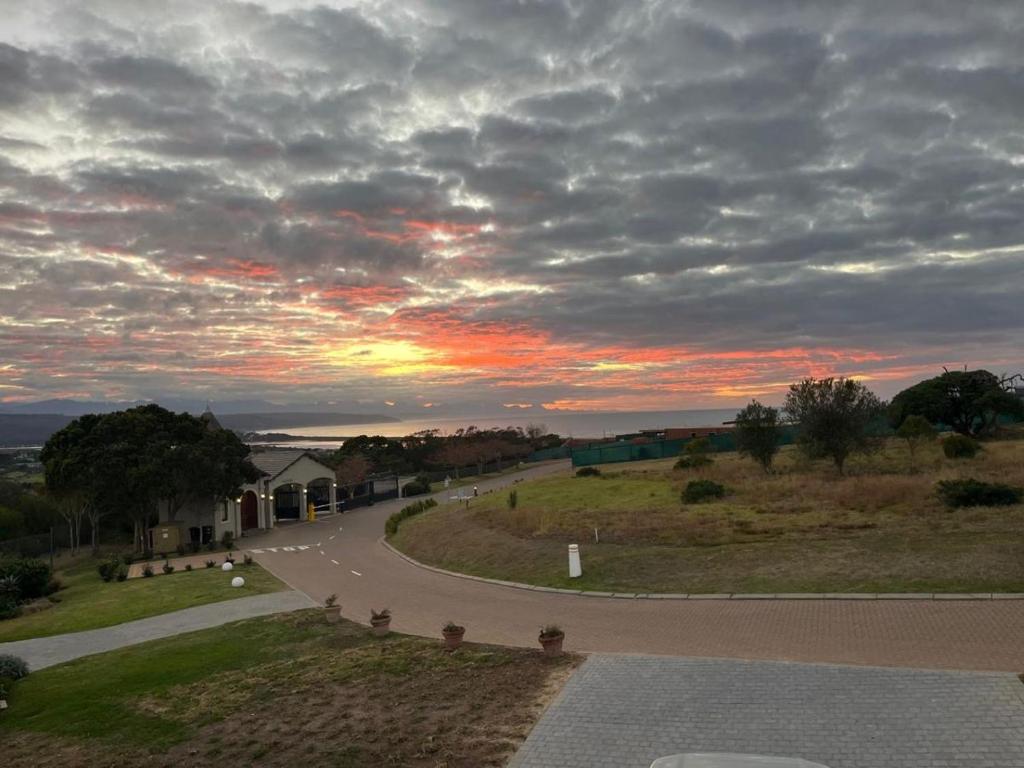 a winding road with a sunset in the sky at Blissful Barons View in Plettenberg Bay