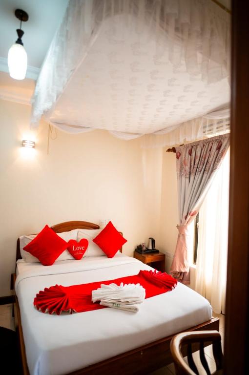 a bedroom with a white bed with red pillows at Explora Lodge in Arusha
