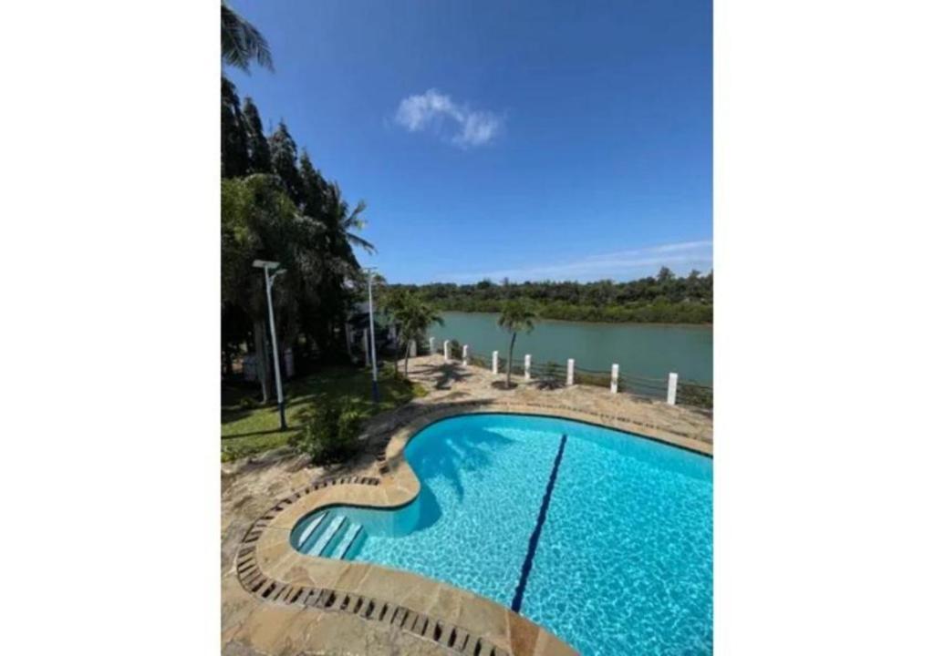 a swimming pool next to a body of water at Mango Villa Mtwapa in Mtwapa
