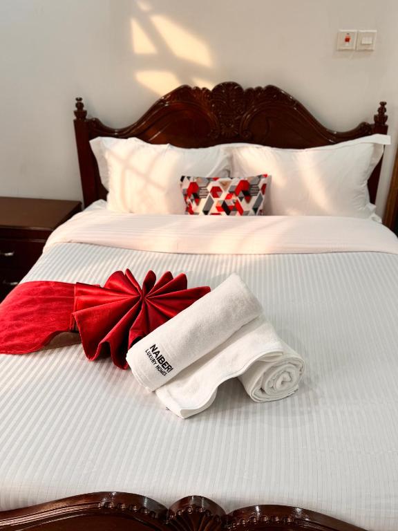 a bed with two towels and a red bow at NAIBERi LUXURY HOME in Eldoret
