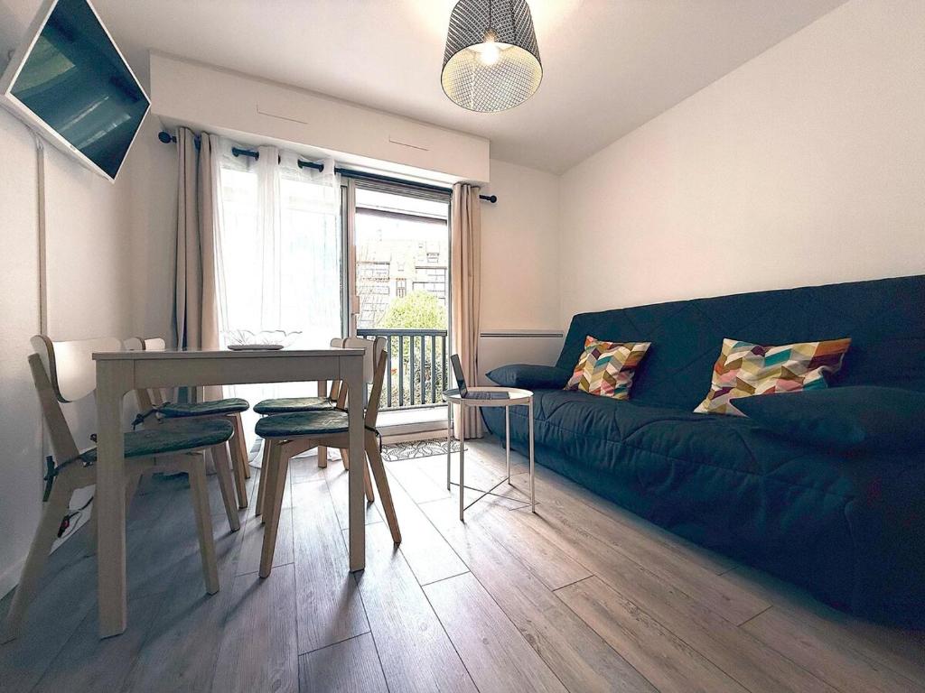 a living room with a blue couch and a table at Appartement tout confort très proche mer in Villers-sur-Mer
