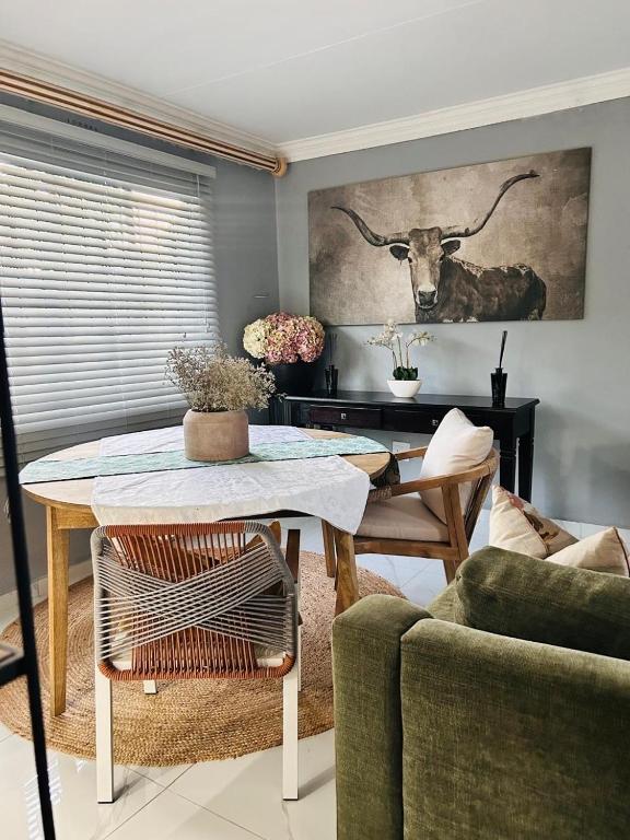 a living room with a table and a cow on the wall at 33OnPangolin B&B in Nelspruit