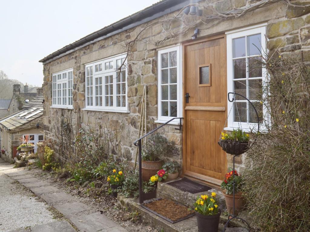 a stone house with a wooden door and windows at The Pottery Annexe in Baslow