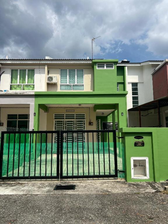 a green and white house with a black fence at Teratak Amaris Homestay MELAYU ONLY in Sungai Petani