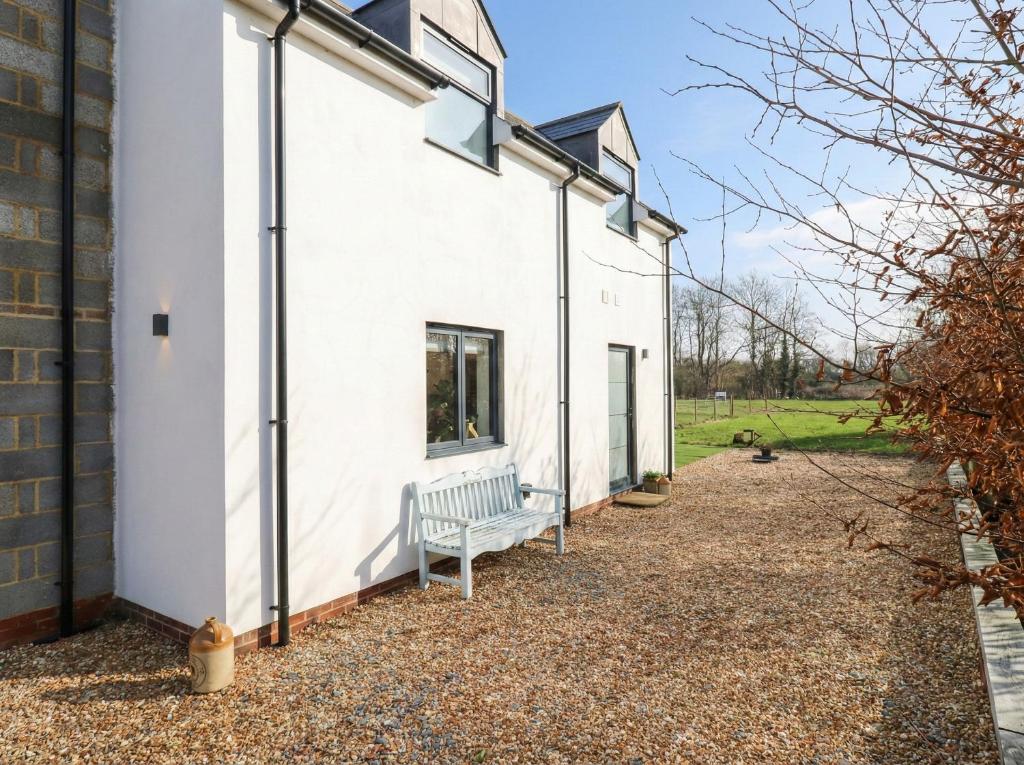 a white house with a bench on the side of it at The Kiln in Bolnhurst