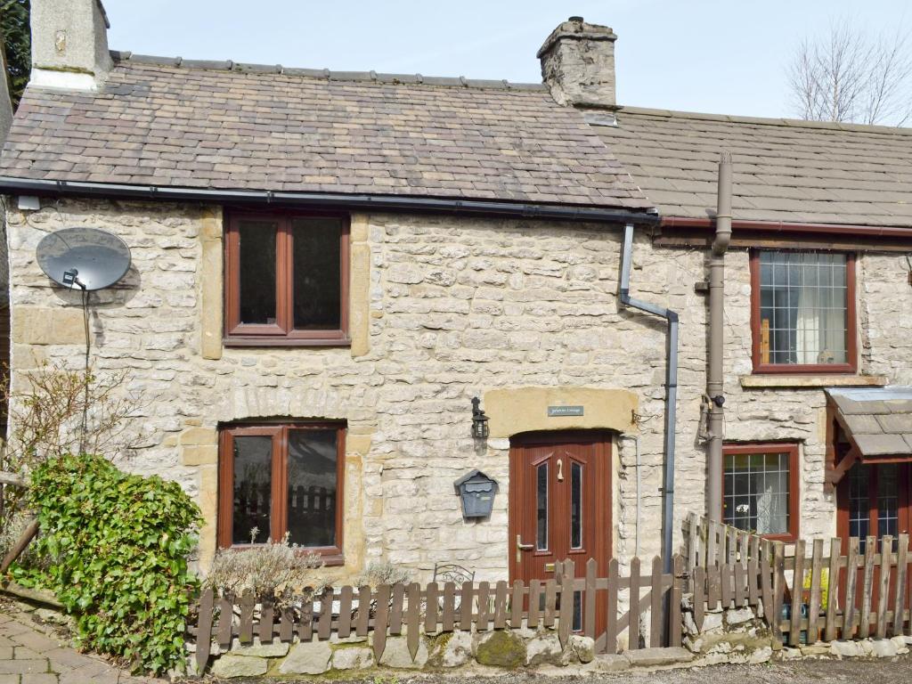 a stone house with a wooden fence in front of it at Jeremiah Cottage in Bradwell
