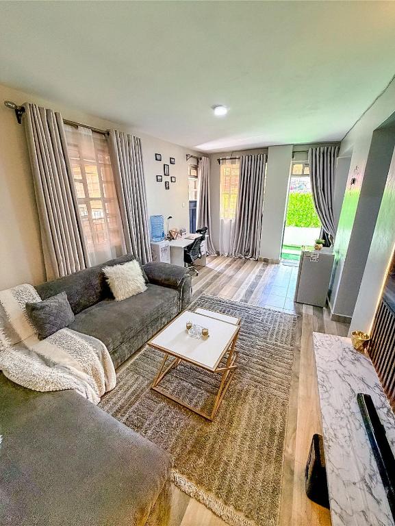 a living room with a couch and a table at Graphite & Gold Suite in Ruiru