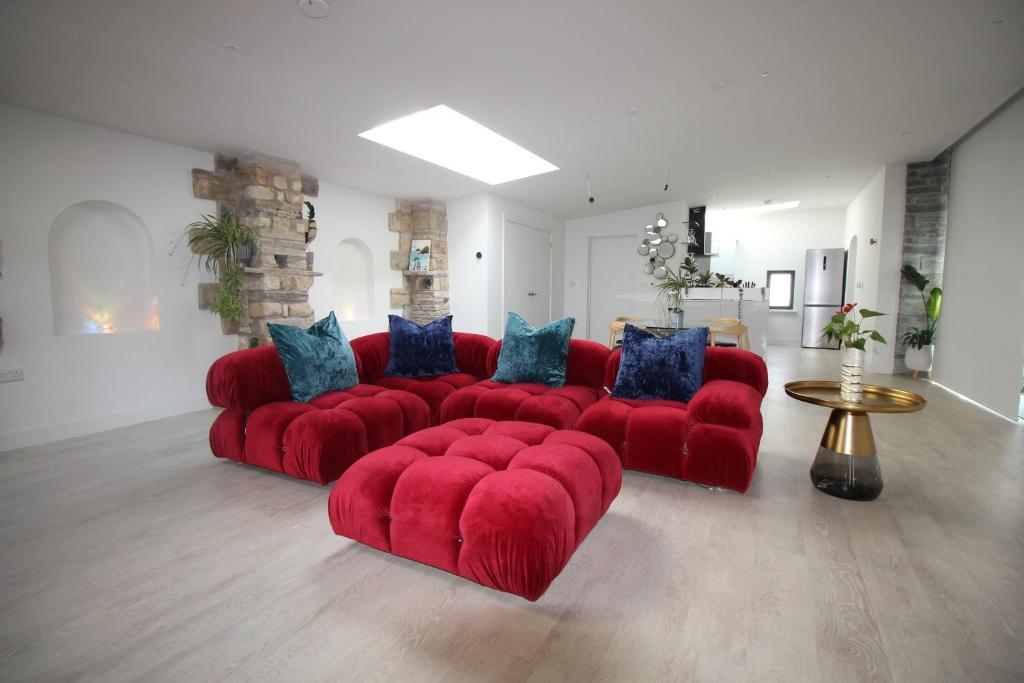 a red couch with blue pillows in a living room at The Old Poolhouse in Beetham