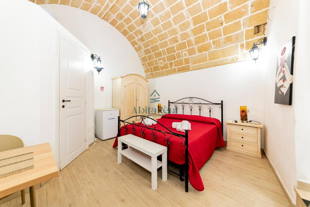 a bedroom with a red bed and a brick wall at Casa di Ponente - Gallipoli in Gallipoli