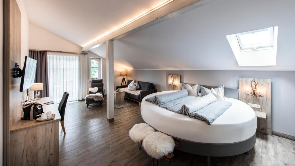 a bedroom with a large white bed and a living room at Sporthotel Bernrieder Hof GmbH in Bernried