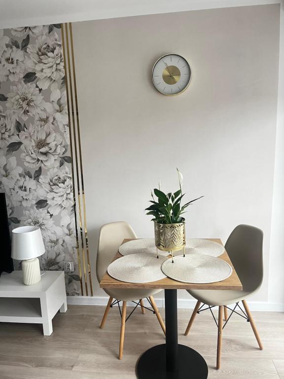a table and chairs in a room with a clock on the wall at Apartament Rynek Strzelin in Strzelin