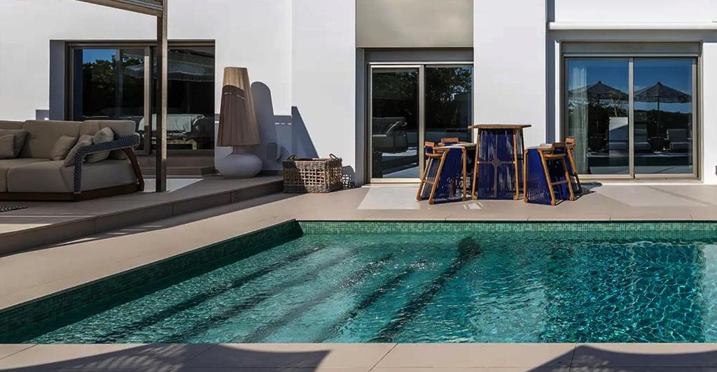 a swimming pool with two chairs and a house at Super views in Mykonos in Psarou