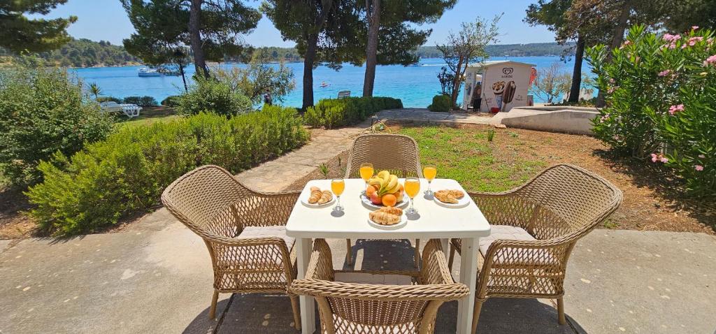a white table with a bowl of fruit on it at Beach front with Swimming pool, Illyria Resort Apt 101 in Milna