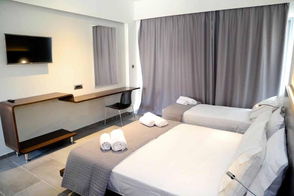 a hotel room with two beds and a desk at Megara Hotel in Megara