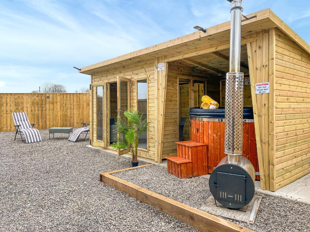a small wooden house with a grill and a guitar at Pasture Barn in Barnard Castle