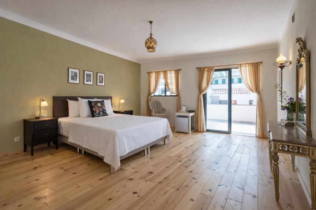 a bedroom with a white bed and a wooden floor at Quinta da Paz B&B in Portimão