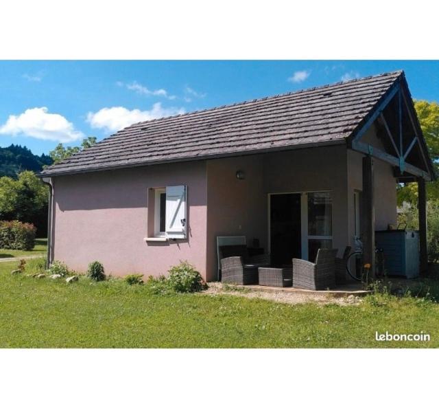 a small house with a window and chairs in the yard at Maisonnette dans son écrin de verdure in Saint-Geniez-dʼOlt