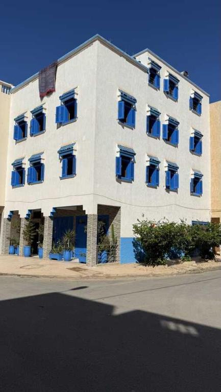 a large white building with blue windows on a street at Résidence chez Said in Sidi Ifni