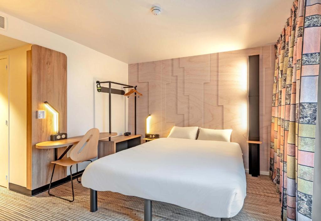 a hotel room with a white bed and a desk at B&B HOTEL Concarneau Keriolet in Concarneau