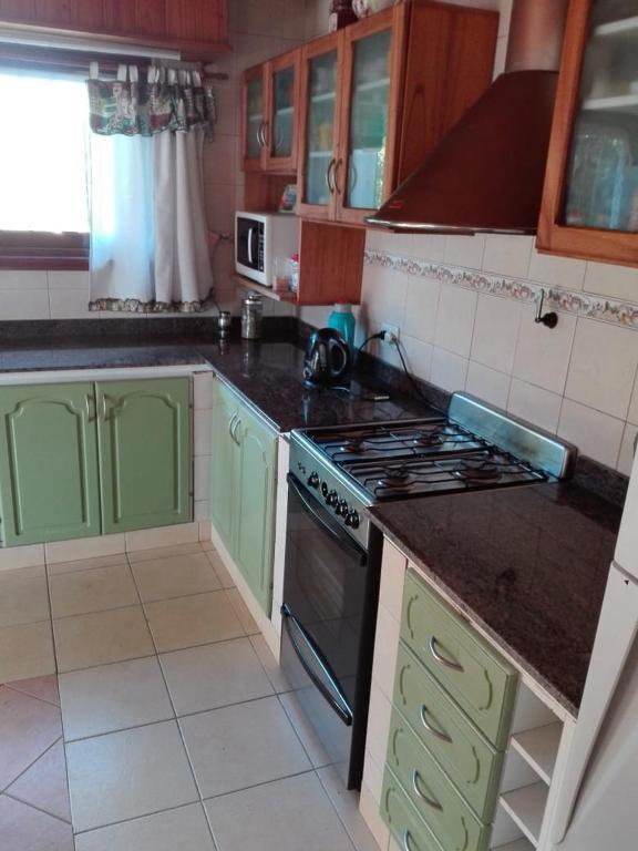 a kitchen with green cabinets and a stove top oven at Chalet con pileta in Miramar