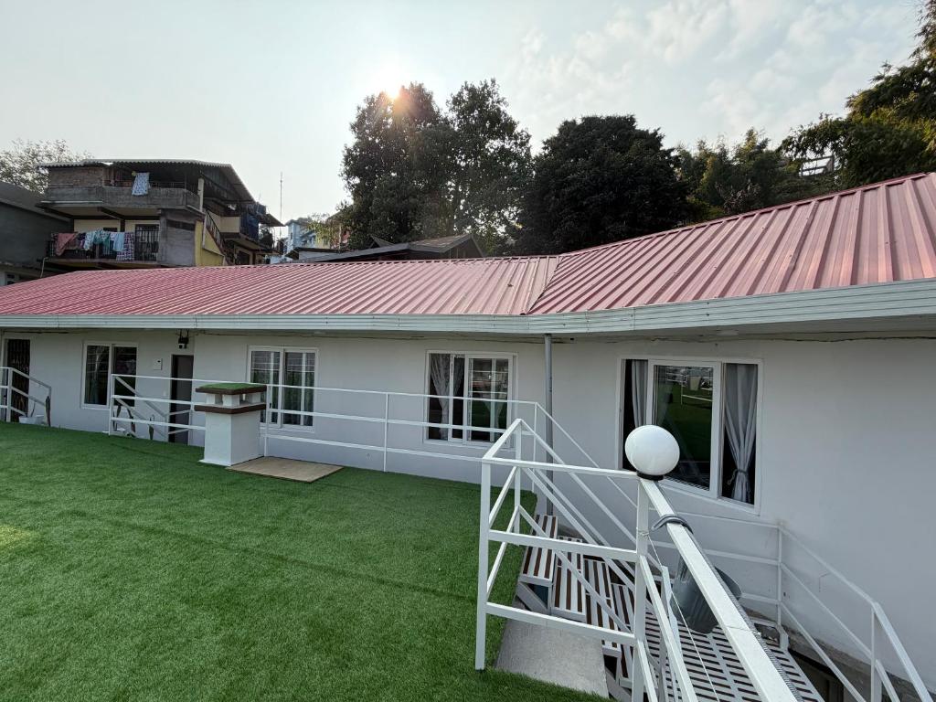 ein weißes Haus mit rotem Dach und einem Hof in der Unterkunft Baas Basai in Kalimpong