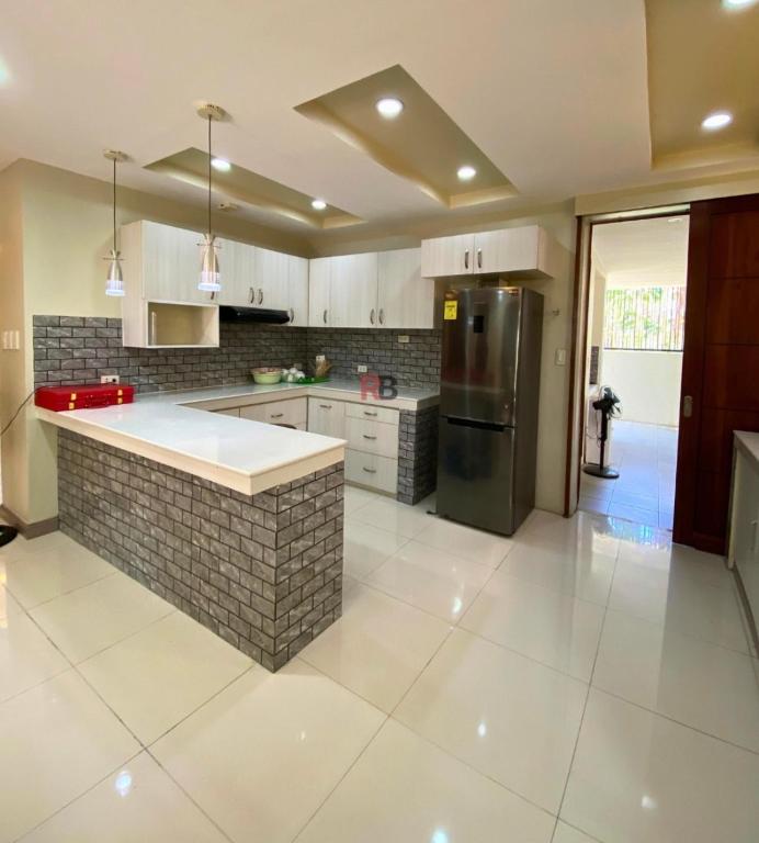 a large kitchen with a counter and a refrigerator at Rathore villa in Lahore