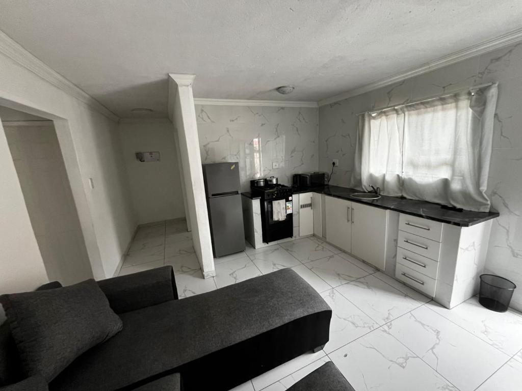 a living room with a couch and a kitchen at Sunset Rest Guesthouse in Secunda