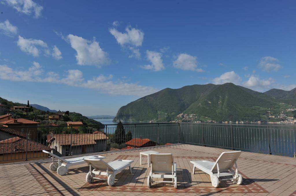 a patio with white chairs and a view of the water at Hotel Bellavista Meublè in Monte Isola