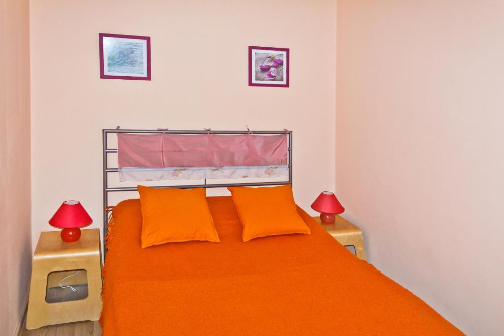 a bedroom with a bed with orange sheets and two lamps at ALLiS-HALL Apartament at Karla Libkknekhta 16 in Yekaterinburg