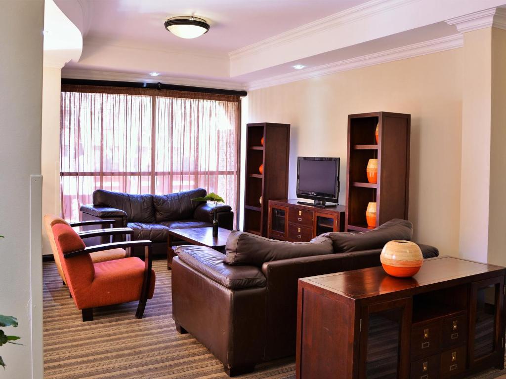 
a living room filled with furniture and a tv at Premier Hotel Pretoria in Pretoria

