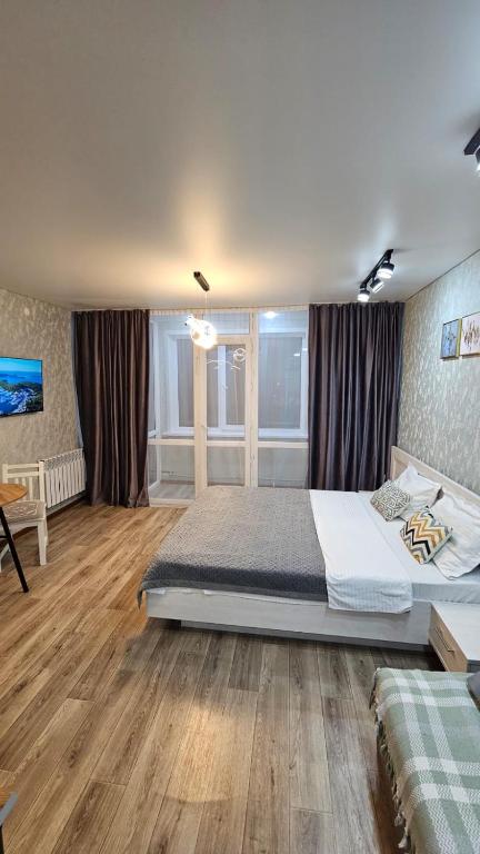 a bedroom with a large bed and a wooden floor at 1 комнатные апартаменты 4а 67 in Semey
