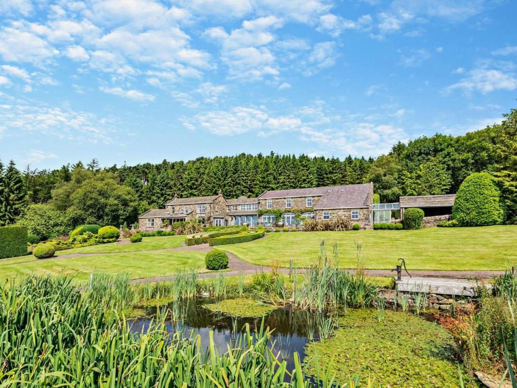 an exterior view of a large house with a pond at 5 Bed in Otley oc-95414 in Fewston