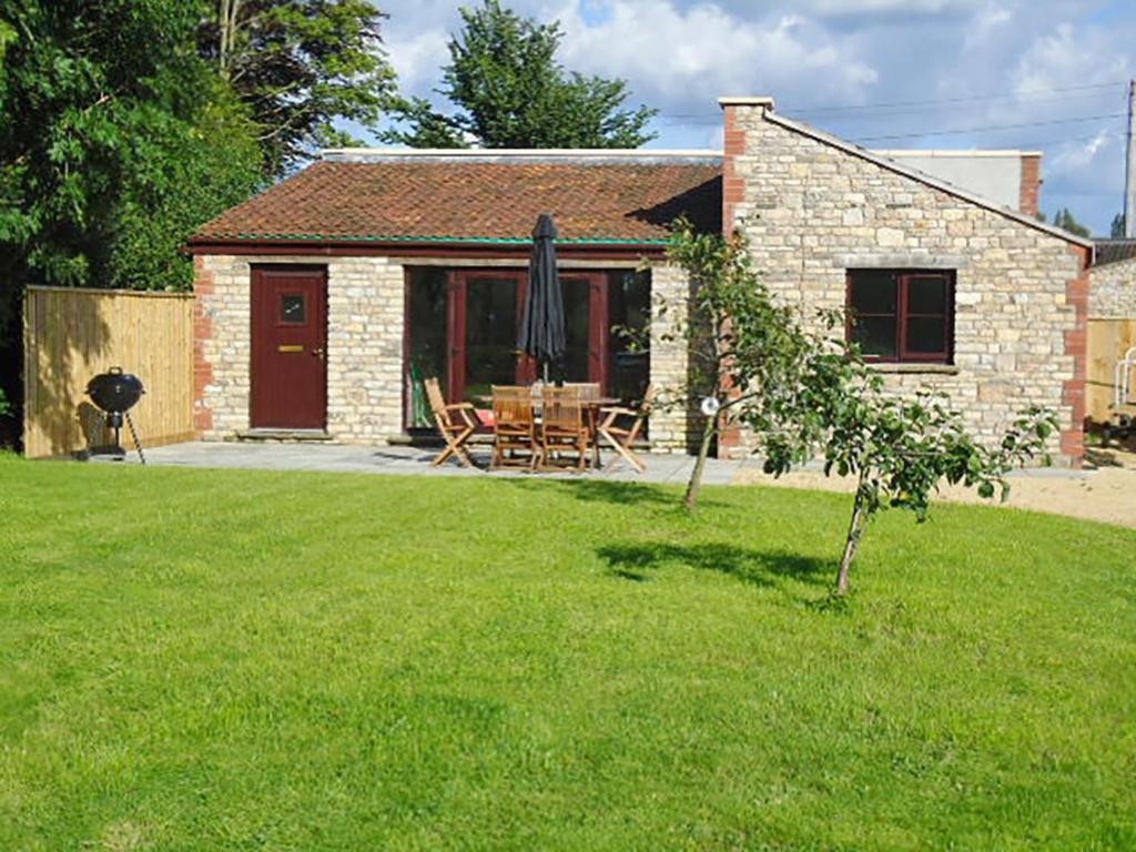a brick house with a table and an umbrella in a yard at 2 Bed in Chew Magna oc-chela in Stowey