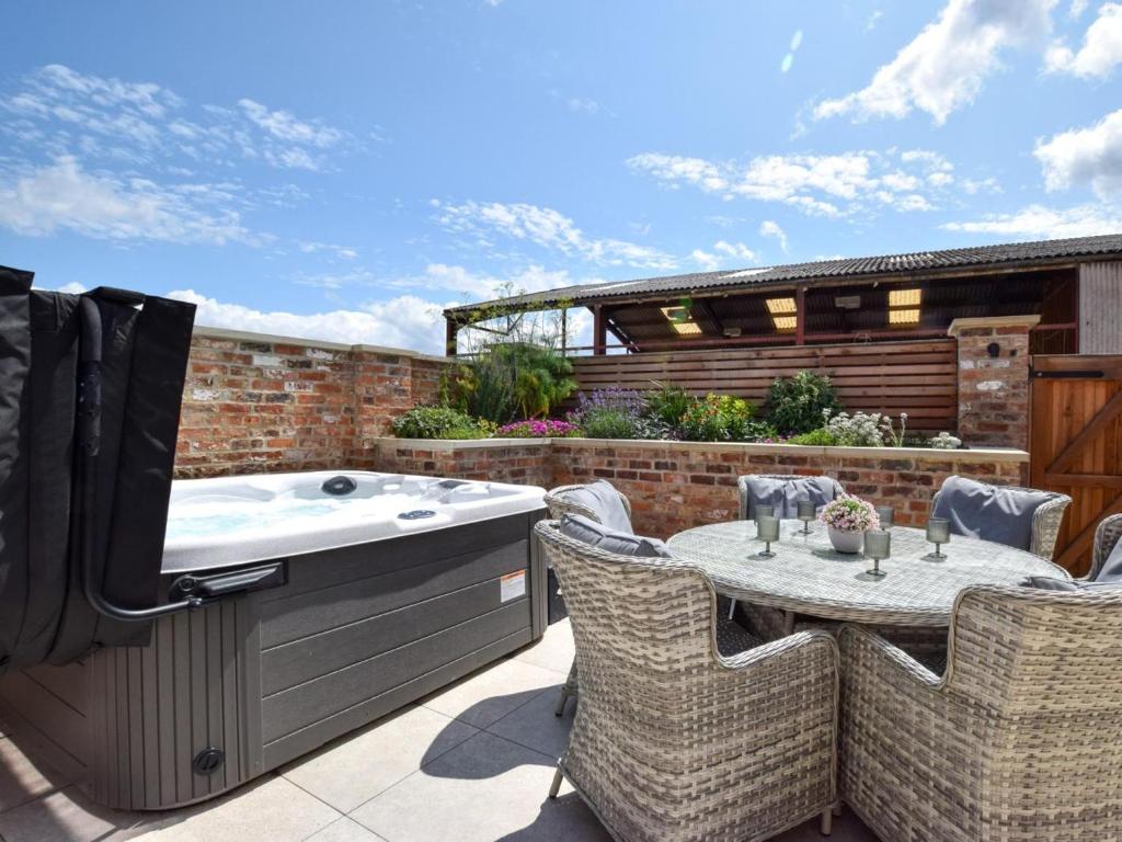a patio with a hot tub and a table and chairs at 3 Bed in York oc-93898 in Tollerton