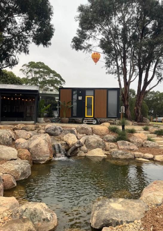 a tiny house with a pond in front of it at Gruyere Falls by Tiny Away in Gruyere
