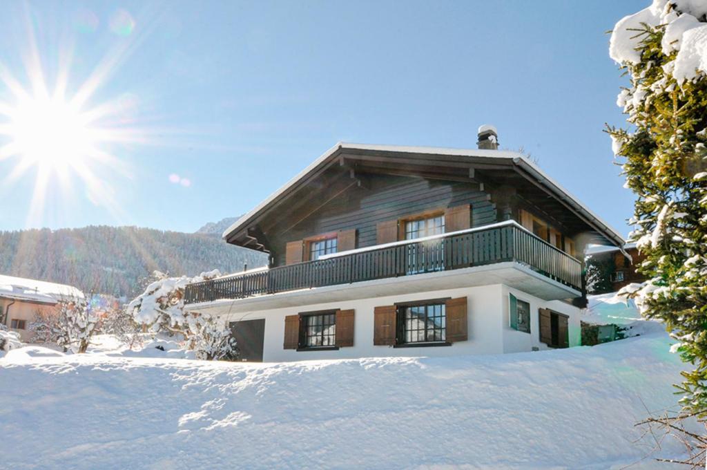 a house in the snow with the sun in the background at Les Cassis in Nendaz