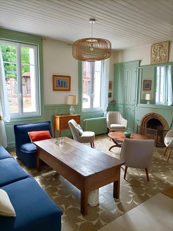 a living room with a blue couch and a table at Le Cinquante-Trois, Maison Normande d'exception pour familles - Côte d'Albâtre in Saint-Valery-en-Caux