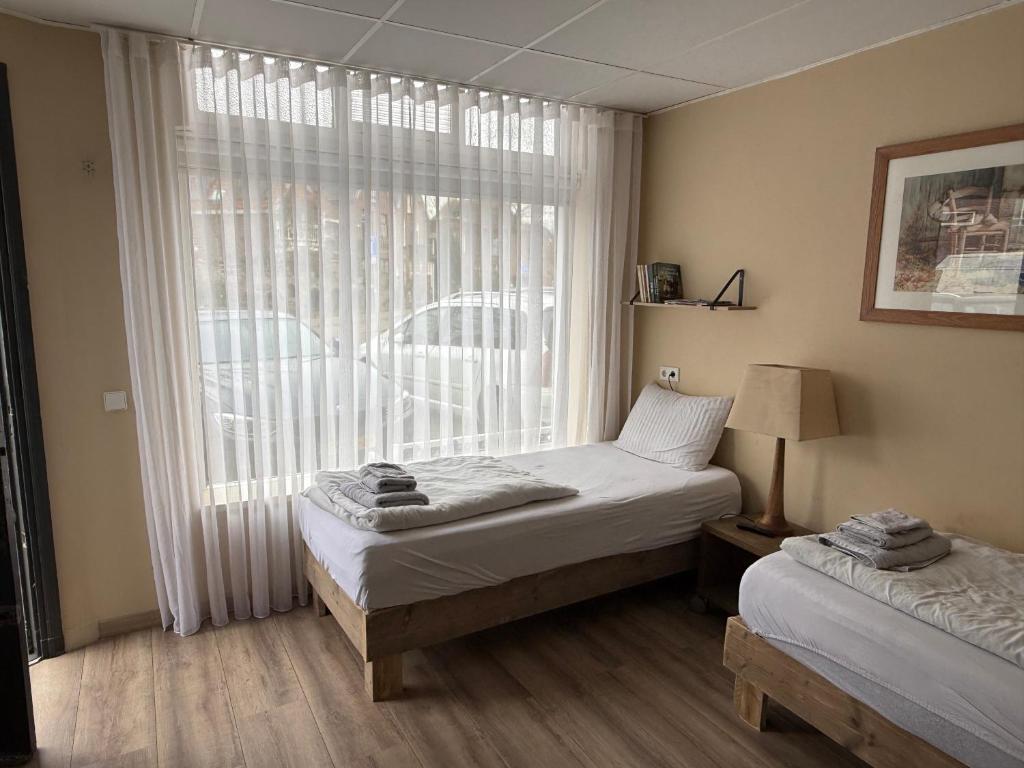 a bedroom with two beds and a large window at Studio Huzur in Deventer