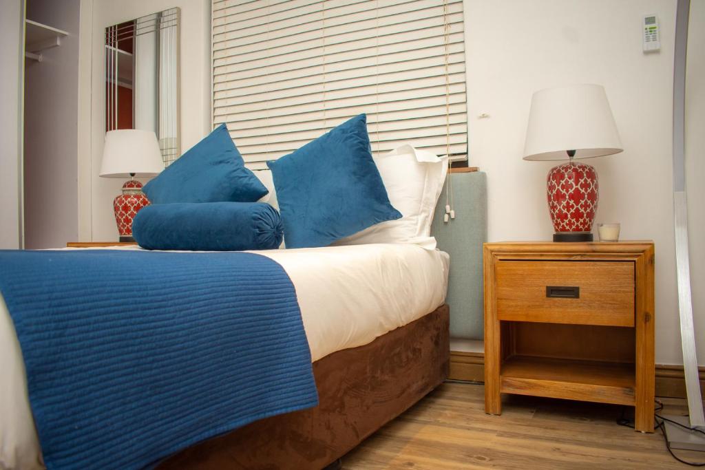 a bedroom with a bed with blue and white pillows at Nkandla Resort in Bulawayo