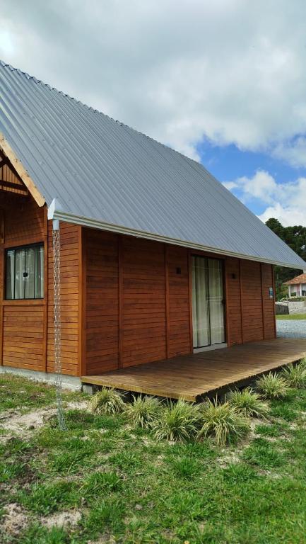 a house with a wooden deck on the side of it at Chalé Azaléia in Campo Alegre