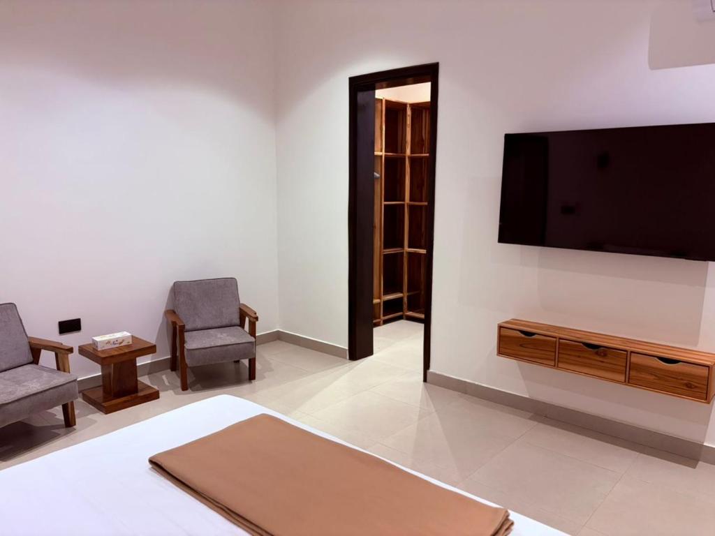 a living room with a flat screen tv and two chairs at Zanziluxe Residences in Zanzibar City