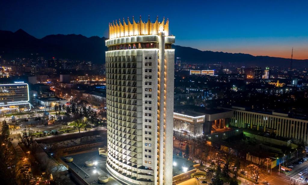a tall white building with lights on top of it at Kazakhstan Hotel in Almaty