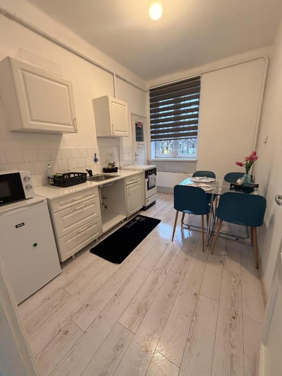 a kitchen with white cabinets and a table and chairs at Downtown Apartman near City Center & Miskolc Plaza in Miskolc