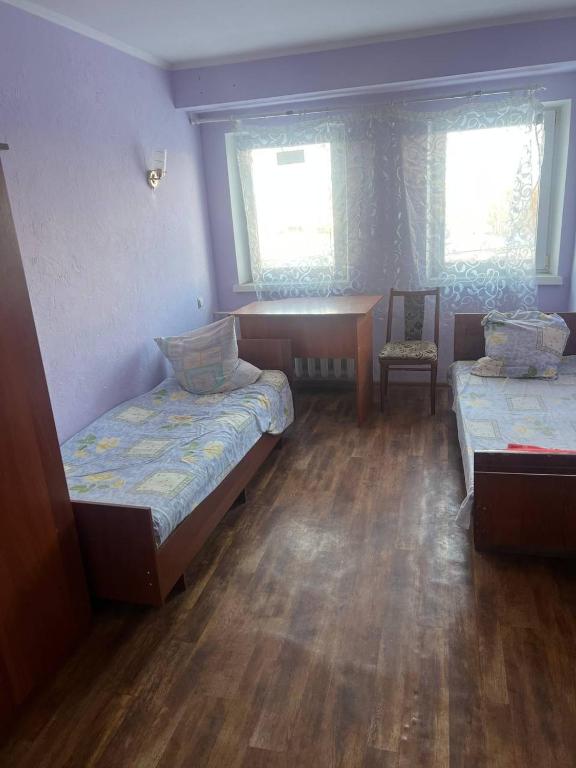 a room with two beds and a desk and two windows at Оазис in Lutsk