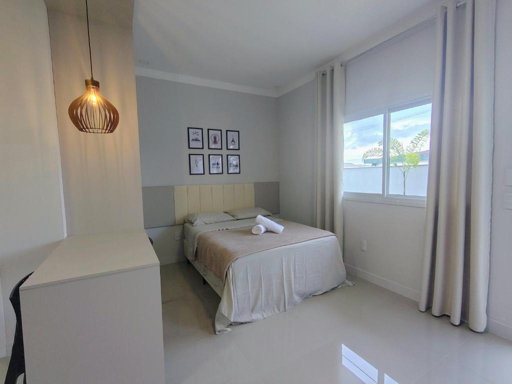 a white bedroom with a bed and a window at Studio 02# Aconchego e tranquilidade em Floripa Muito Top e tranquilo in Florianópolis